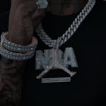 Person wearing a sparkling 'NBA' necklace on a dark background